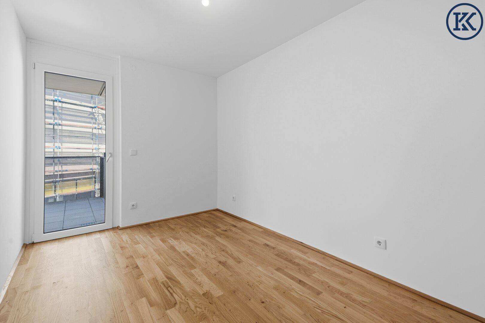 Helles Schlafzimmer mit Eichenparkettboden und direktem Zugang zu einem Balkon.
