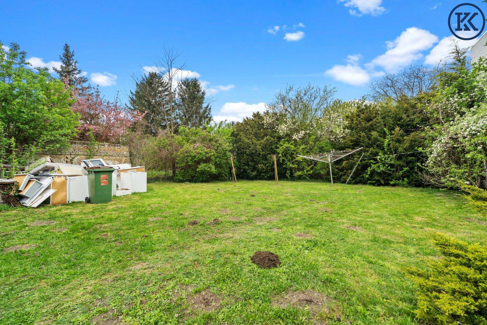 Weitläufiger Garten mit Rasenfläche, Bäumen und Wäscheleine.