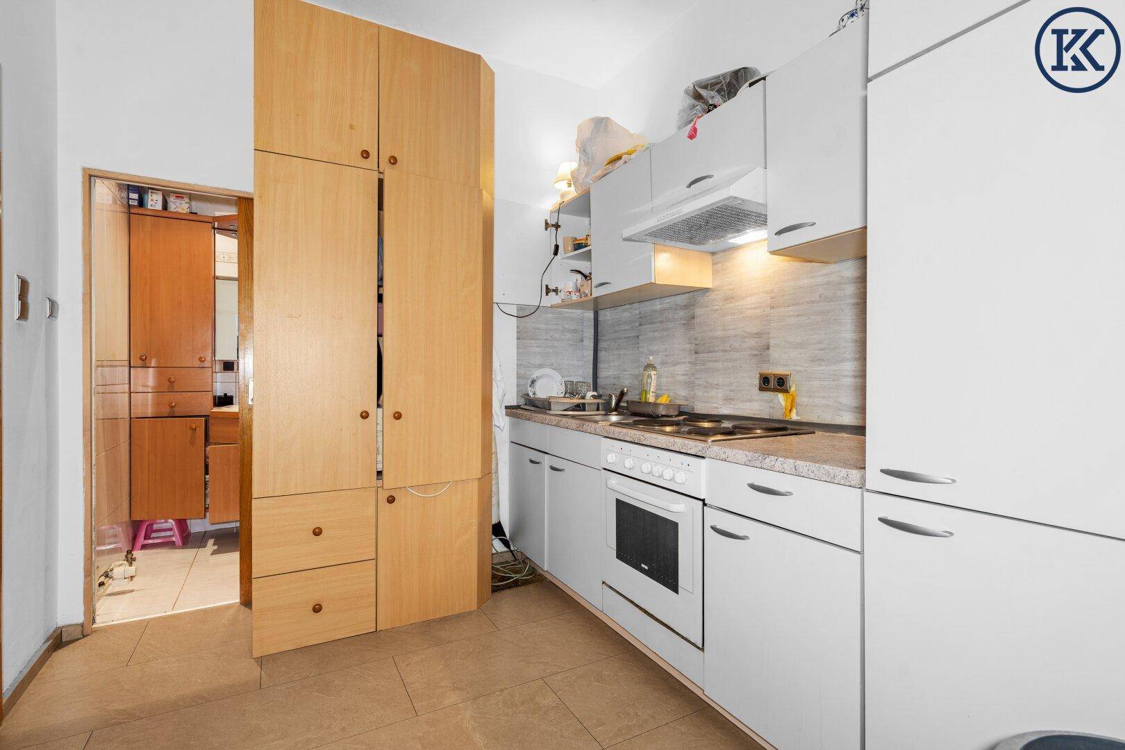 Funktionale Küche mit weißen Schränken, integriertem Backofen und Holzregalen.