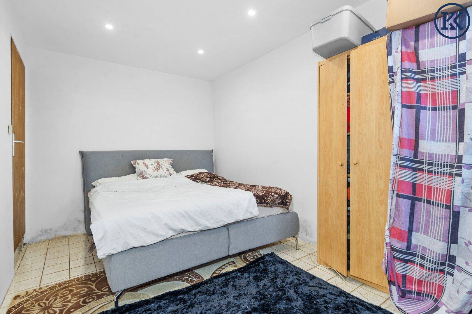 Schlafzimmer mit Doppelbett, Kleiderschrank und gefliestem Boden.