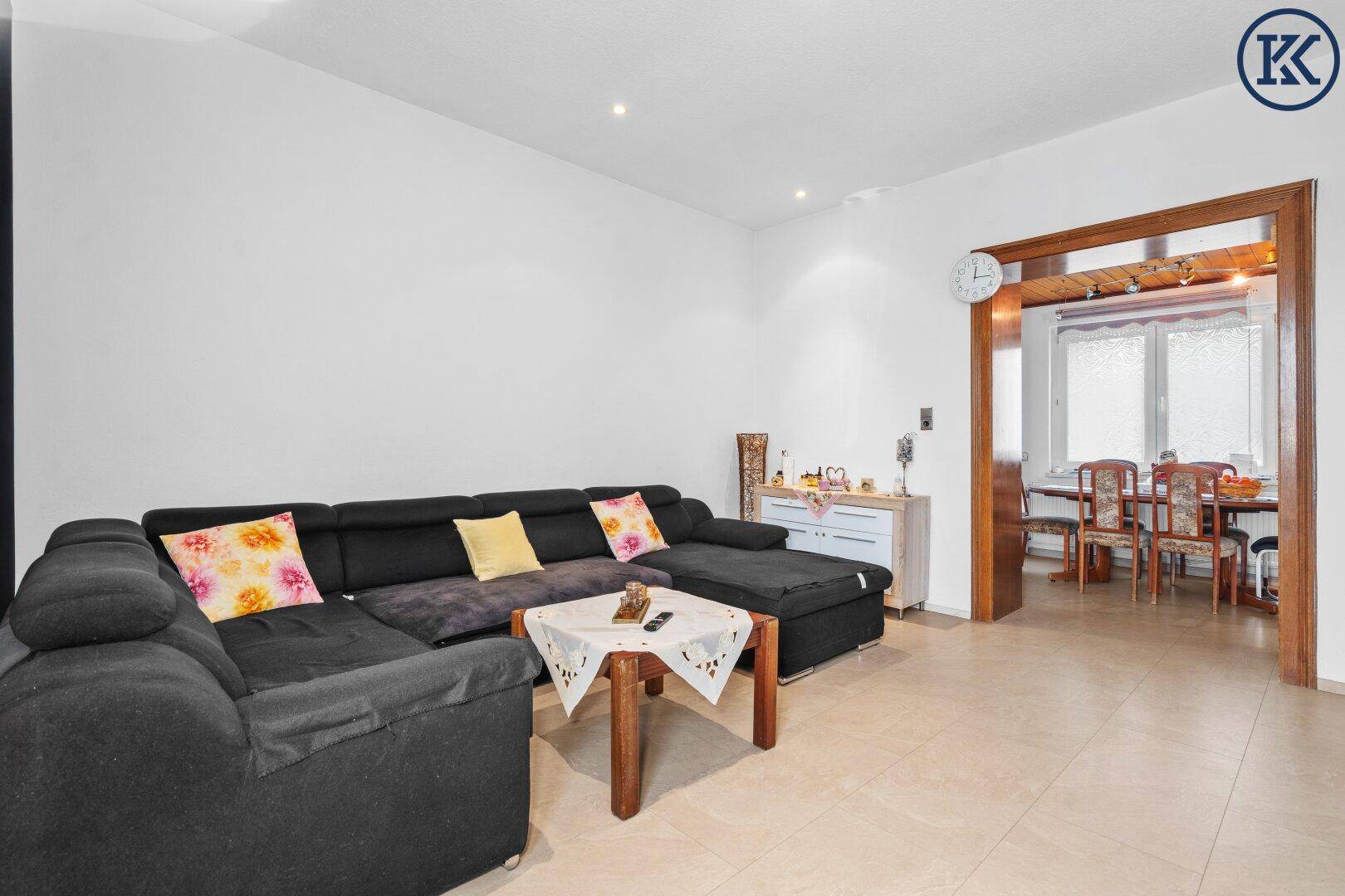 Offener Wohnbereich mit großem Sofa und Durchgang zum Esszimmer.