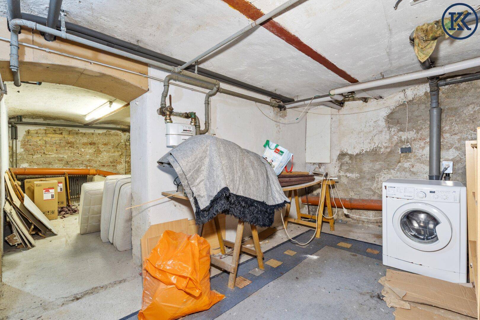 Unfertiger Kellerraum mit Waschmaschine, Rohren und unverputzten Wänden.