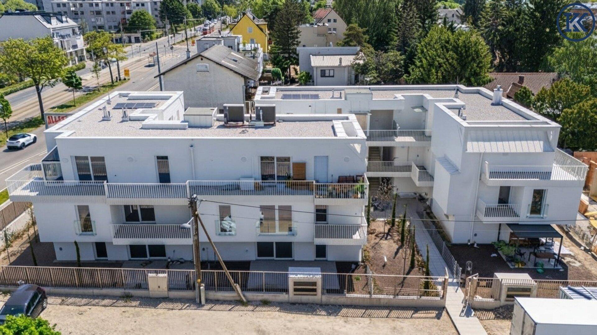 Vogelperspektive auf moderne Wohngebäude mit Flachdächern, Balkonen und umliegender Straße.