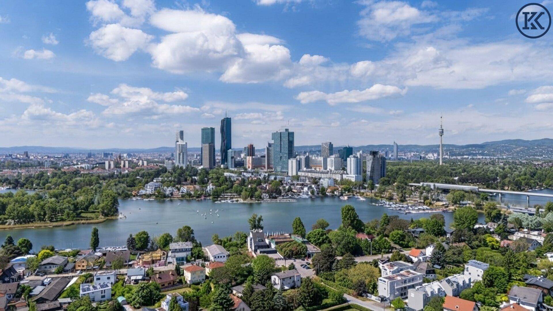 Panoramablick auf die Stadt Wien mit Donau, Hochhäusern und grünen Ufern unter blauem Himmel.