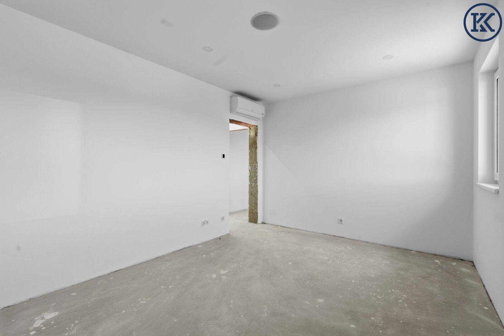 Leeres Zimmer im Rohbau mit einem Fenster und vorbereiteten Wänden, inklusive Klimaanlage.