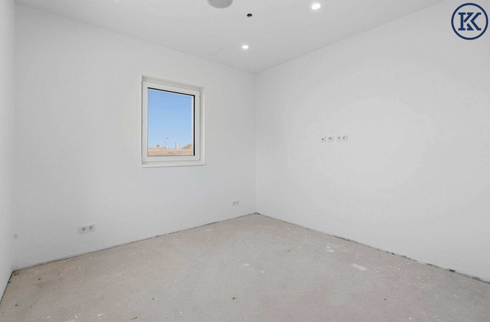 Heller Raum im Rohbau mit einem Fenster und vorbereiteten Wänden, bereit für den Innenausbau.
