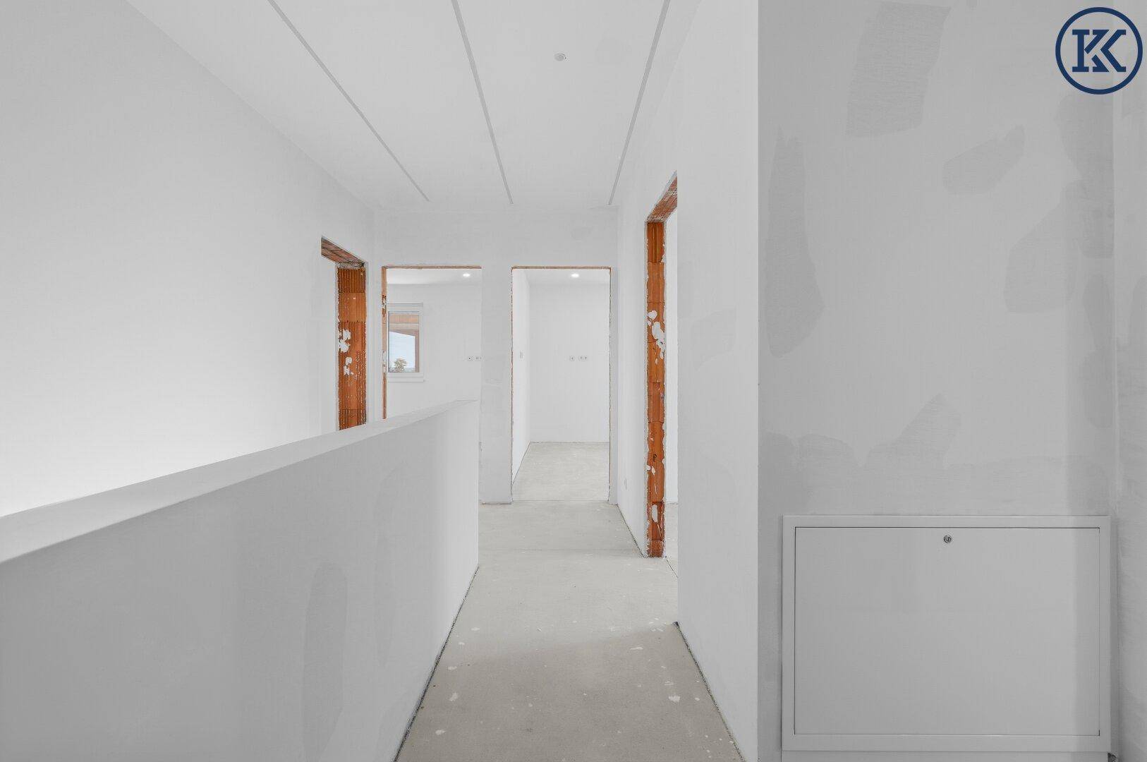 Heller Flur im Rohbau mit mehreren Türöffnungen und vorbereiteten Wänden für den Innenausbau.