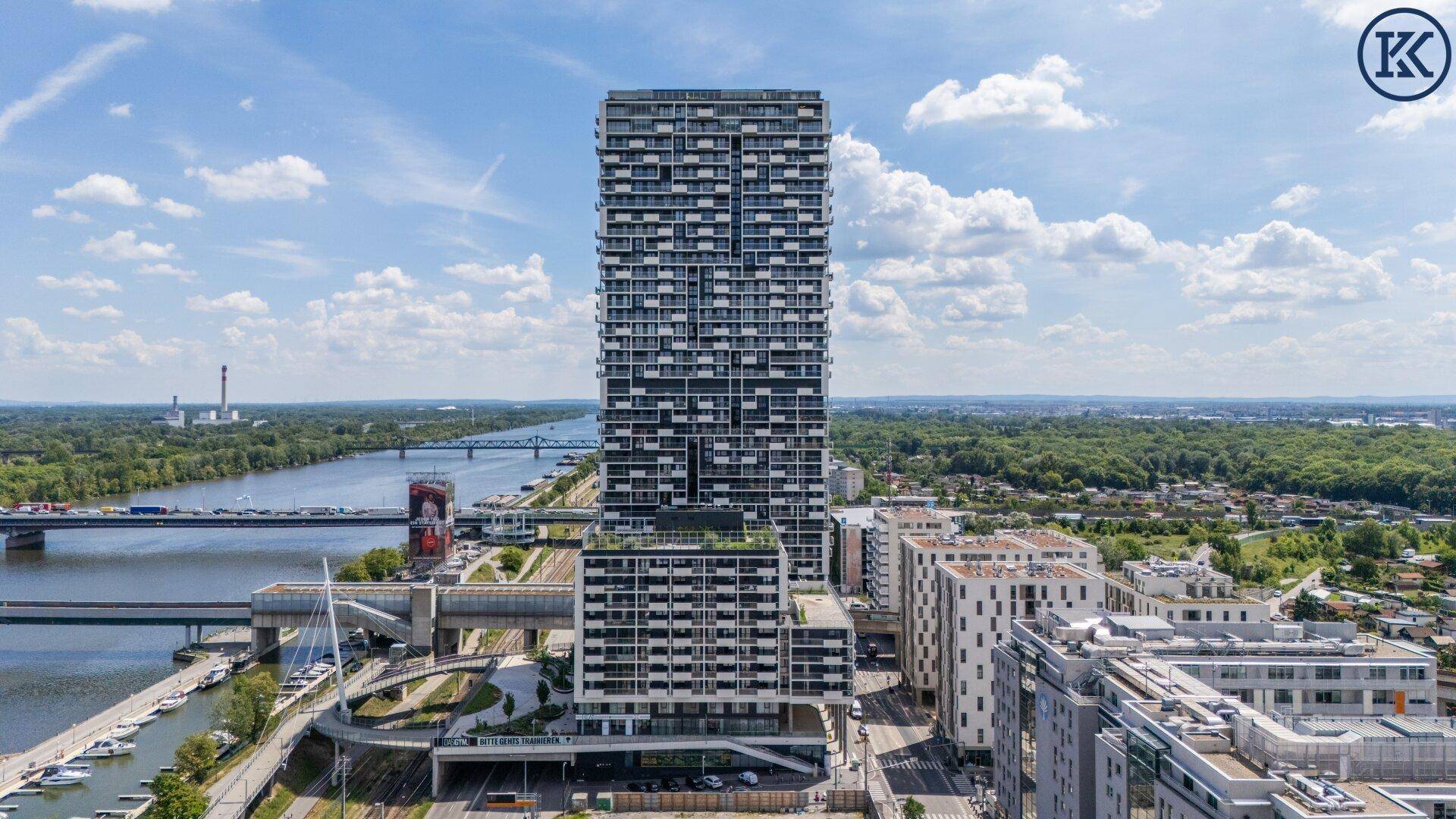 Zeitgenössisches Hochhaus mit Blick auf die Donau, Brücken und die städtische Umgebung.