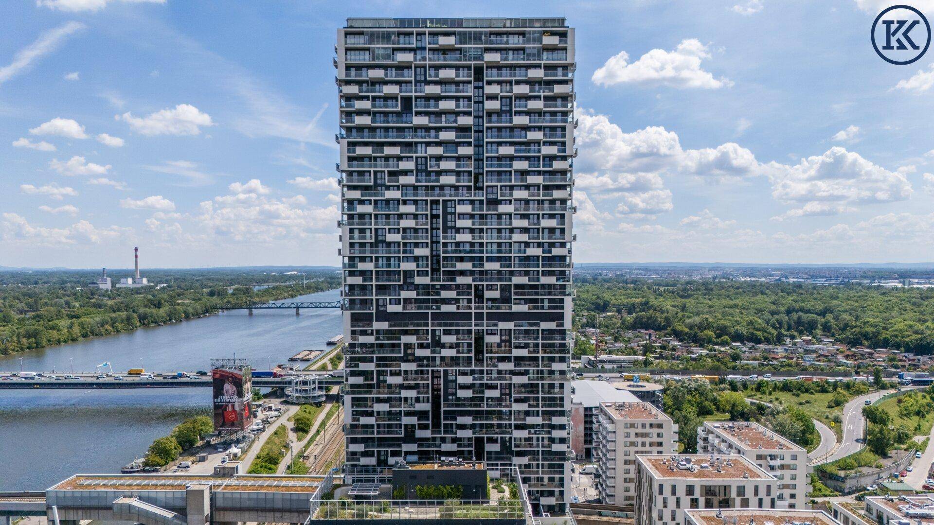 Modernes Hochhaus mit vielen Balkonen und weitem Blick über die Stadt und den Fluss.