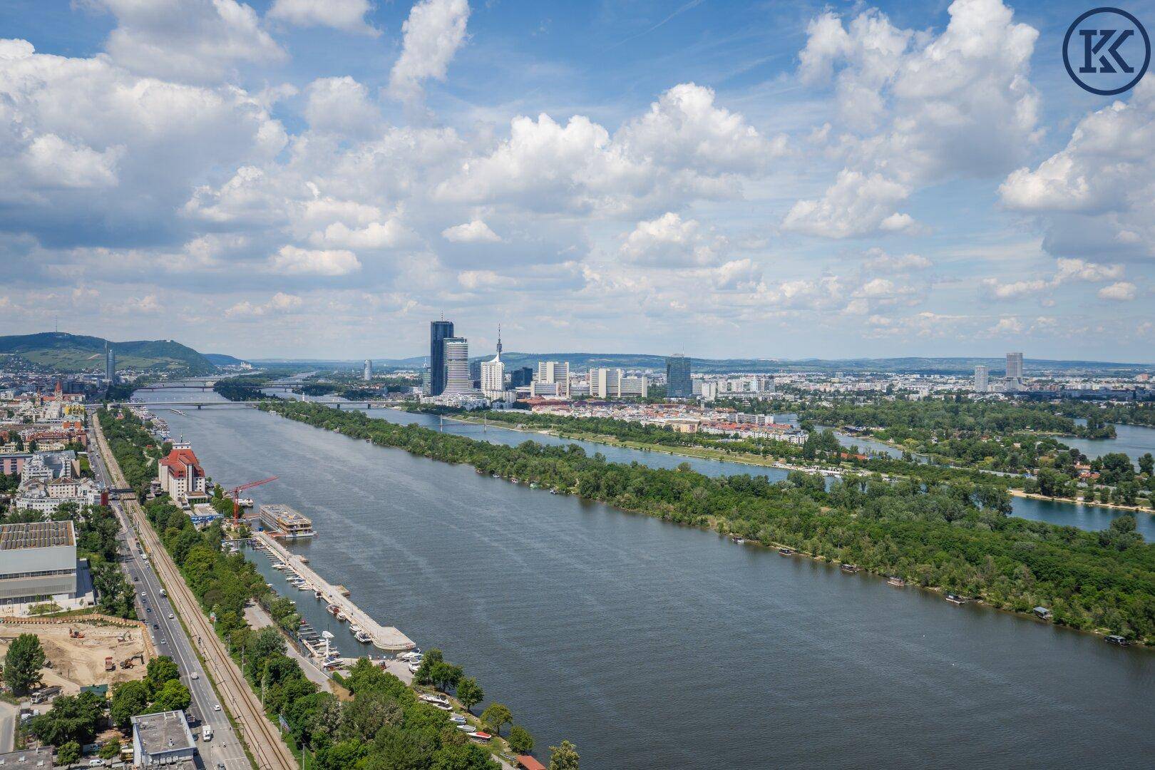 Panoramablick auf die Donau und die Wiener Skyline mit modernen Gebäuden und Brücken.