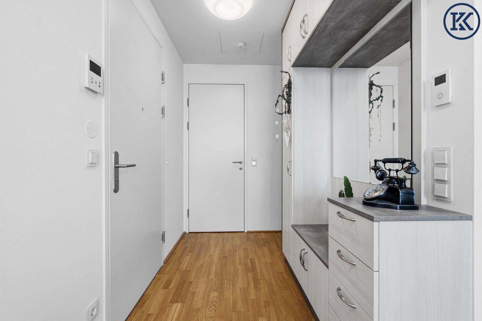 Eingangsbereich einer Wohnung mit Holzfußboden und praktischer Garderobe mit Spiegel.