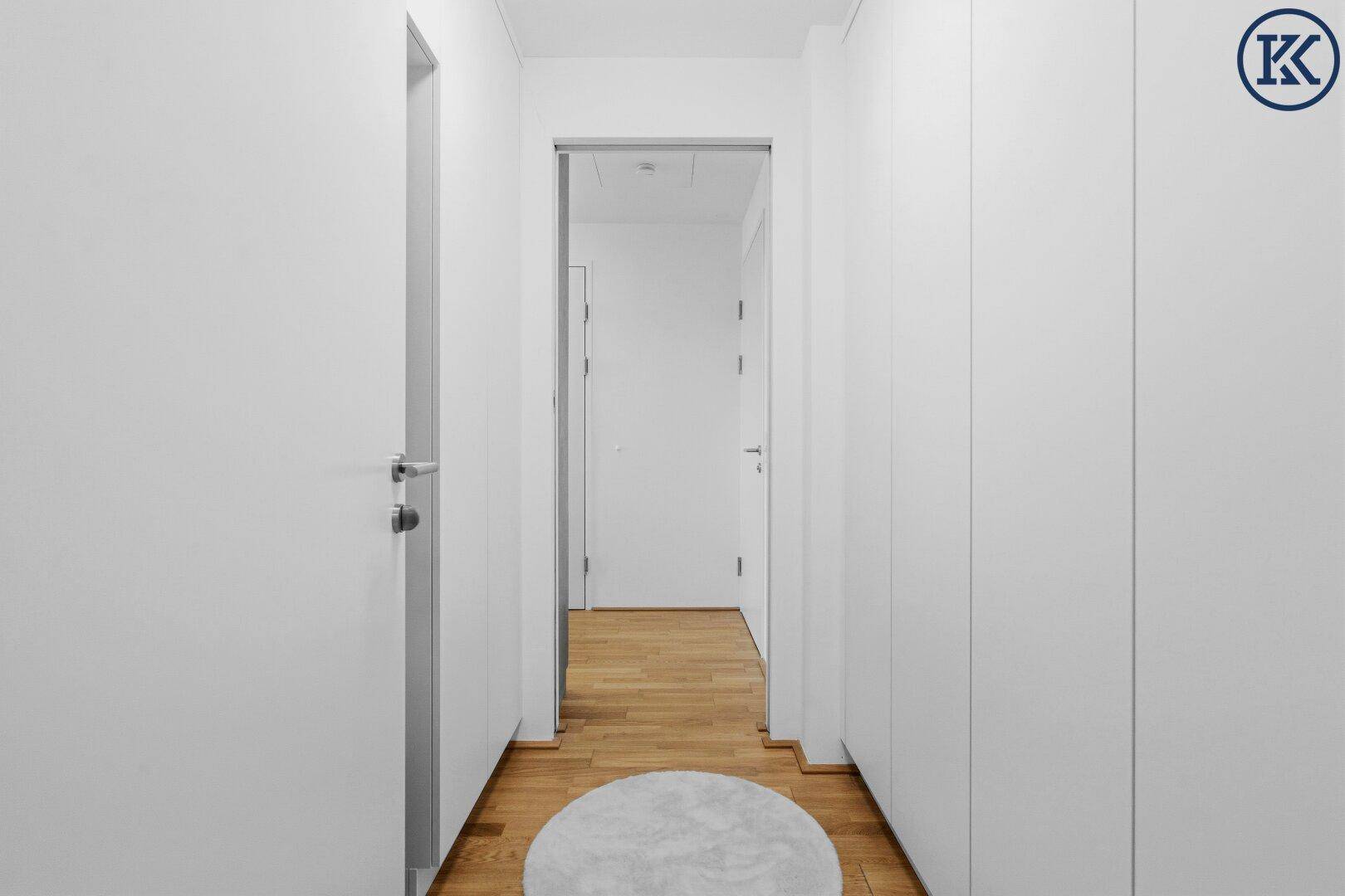 Heller Flur mit integrierten Schränken und Holzboden, der zu weiteren Räumen führt.