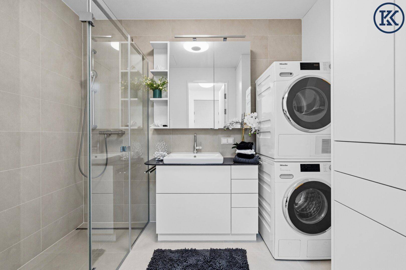 Modernes Badezimmer mit begehbarer Dusche, Waschbecken und integrierter Waschmaschine und Trockner.