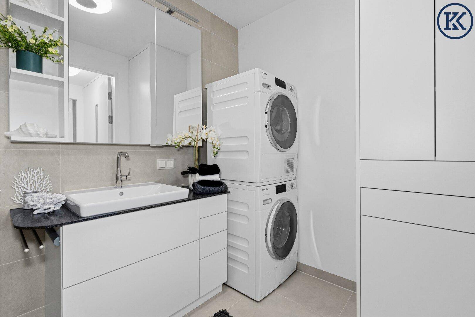 Helles Badezimmer mit Waschmaschine und Trockner, integriert neben dem Waschbecken.