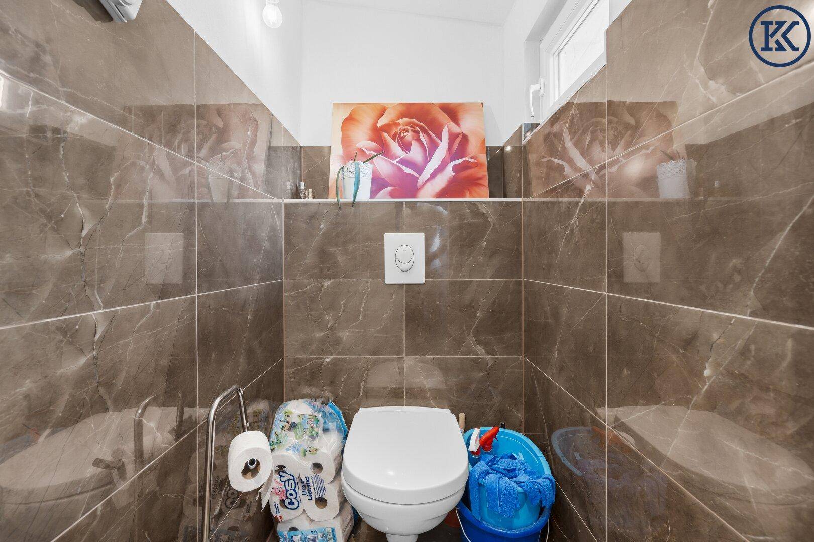 Kleines WC mit dunklen Marmoroptik-Fliesen und einer Toilette, funktional und pflegeleicht.
