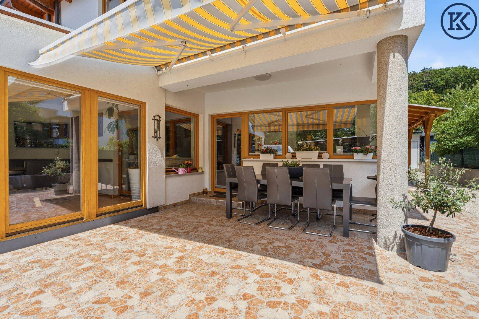 Überdachte Terrasse mit Esstisch und Stühlen, ideal für Mahlzeiten im Freien.
