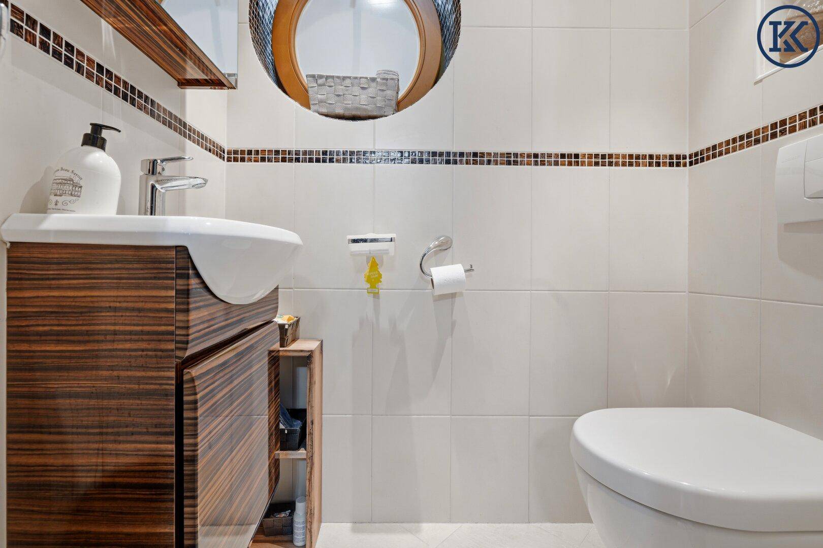 Modernes Gäste-WC mit Holzelementen, weißem Waschbecken und Wand-WC.
