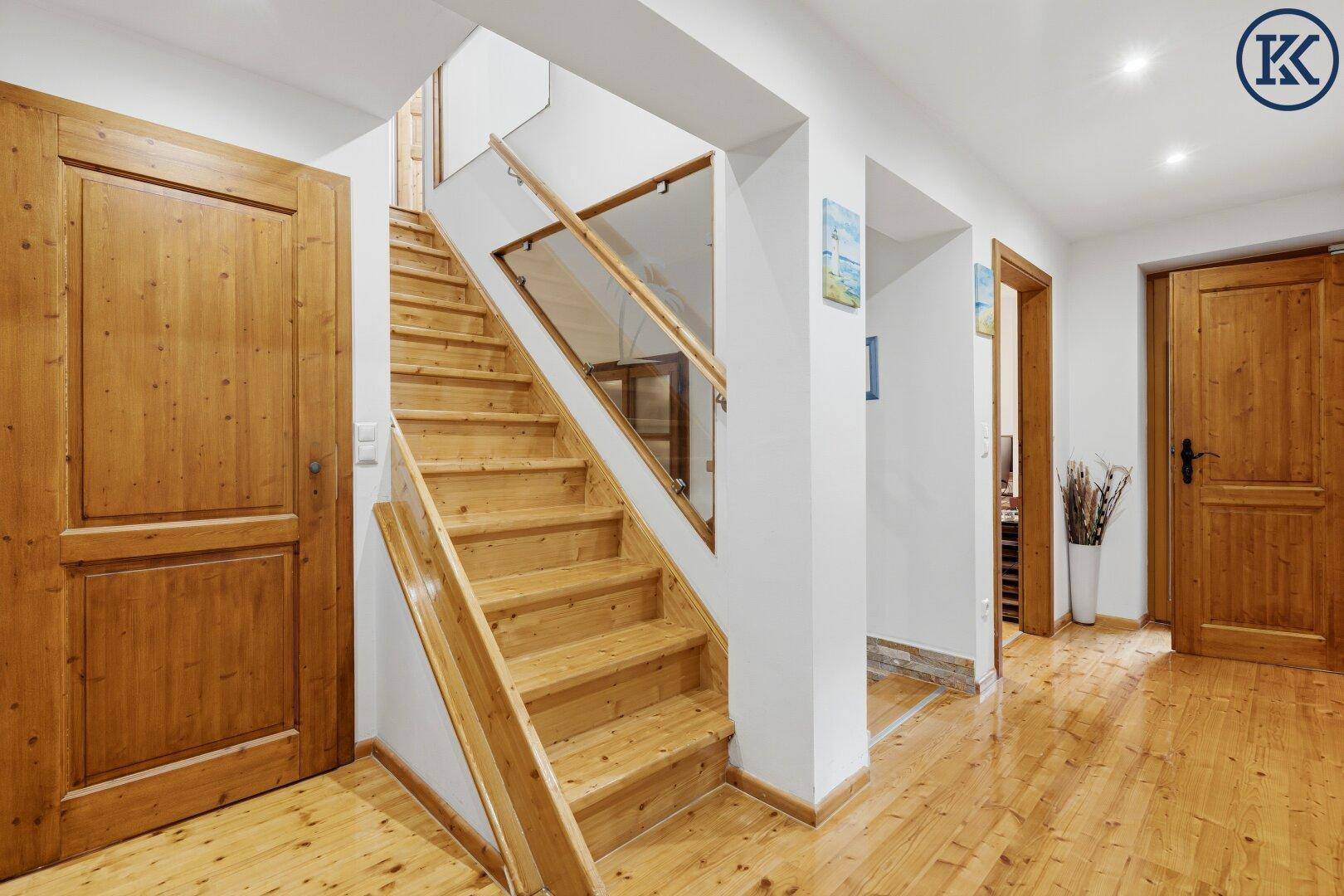 Heller Flur mit Holztreppe, Holzboden und Zugang zu weiteren Räumen.
