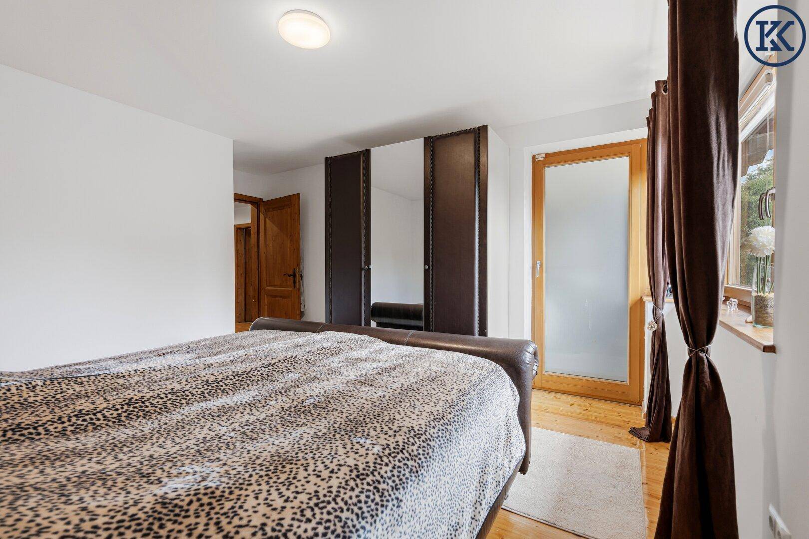 Schlafzimmer mit Doppelbett, Holzboden und Zugang zu einem weiteren Raum.