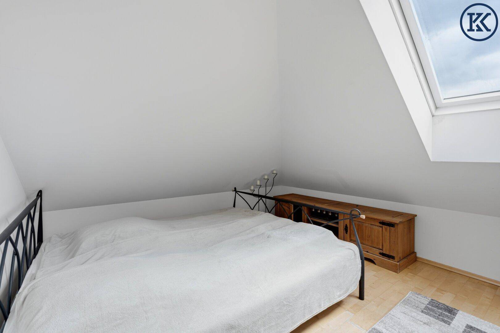 Gemütliches Schlafzimmer im Dachgeschoss mit Dachfenster und Holzboden.