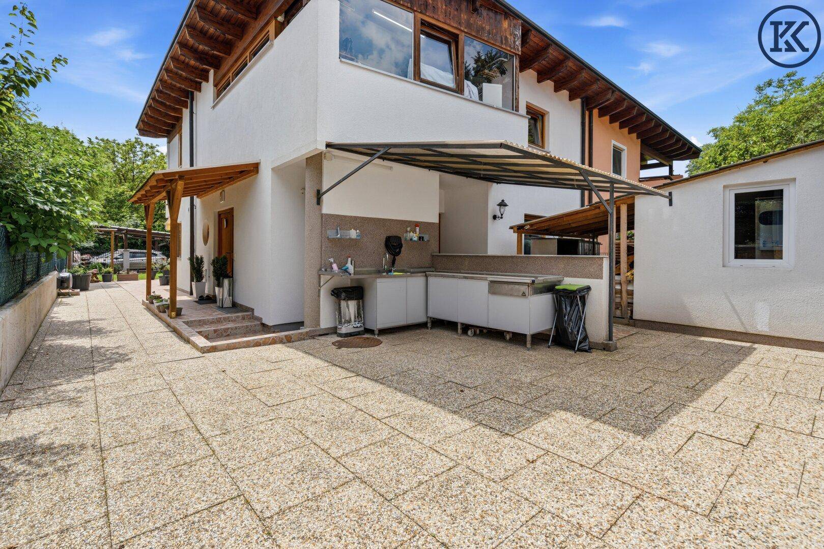 Außenküche mit Arbeitsflächen und Spüle auf einer gepflasterten Terrasse.