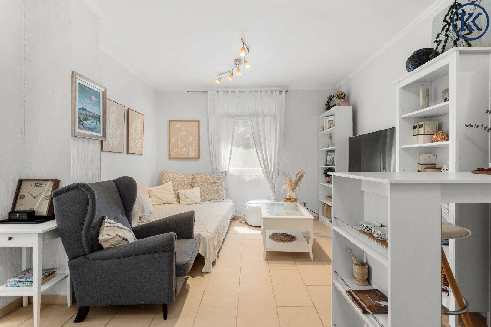 Heller Wohnbereich mit Sessel, Tagesbett und Regalen, ideal zum Entspannen.