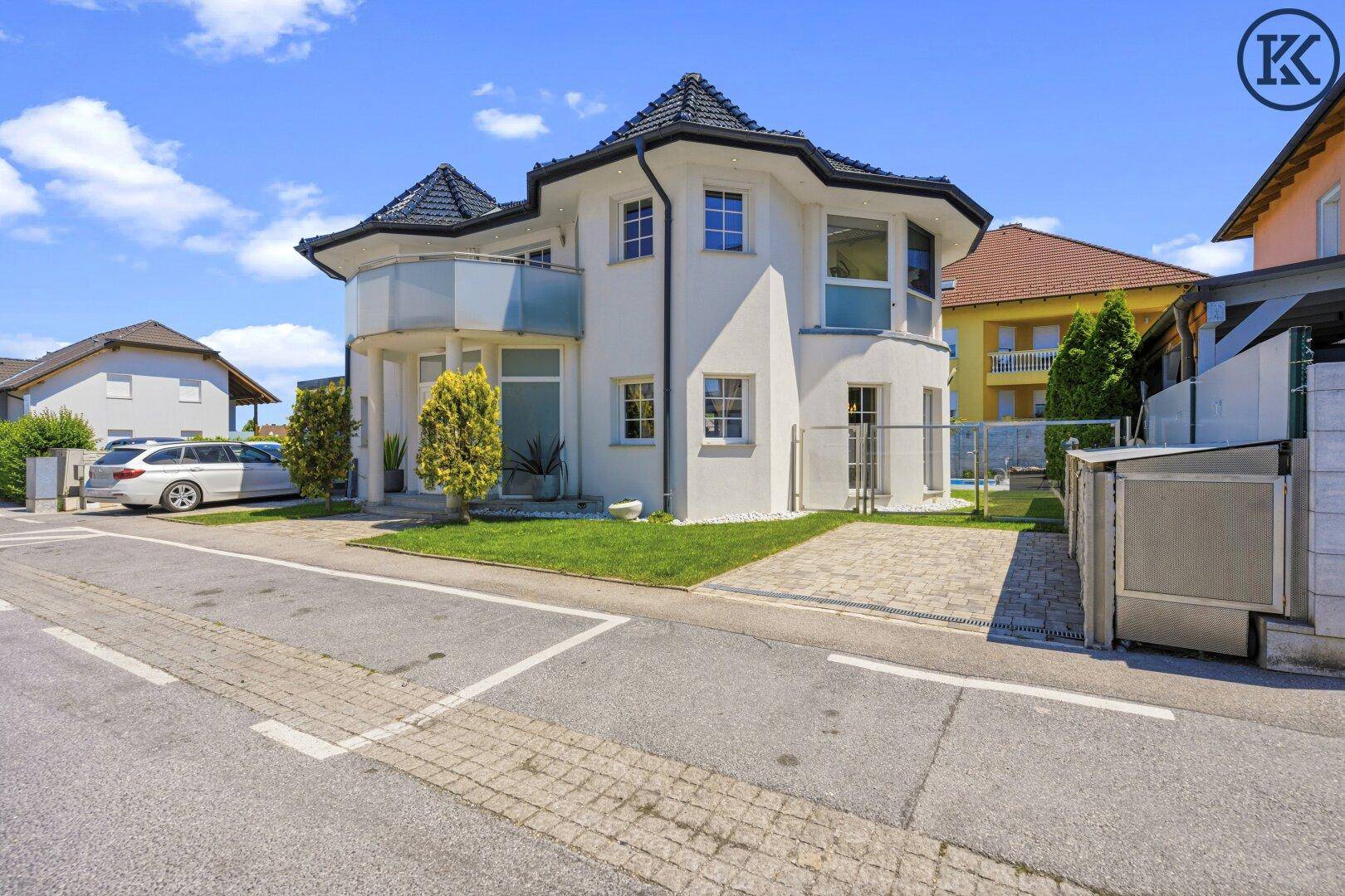Stilvolle Villa mit großzügigem Vorgarten, eleganter Fassade und seitlichem Zugang.