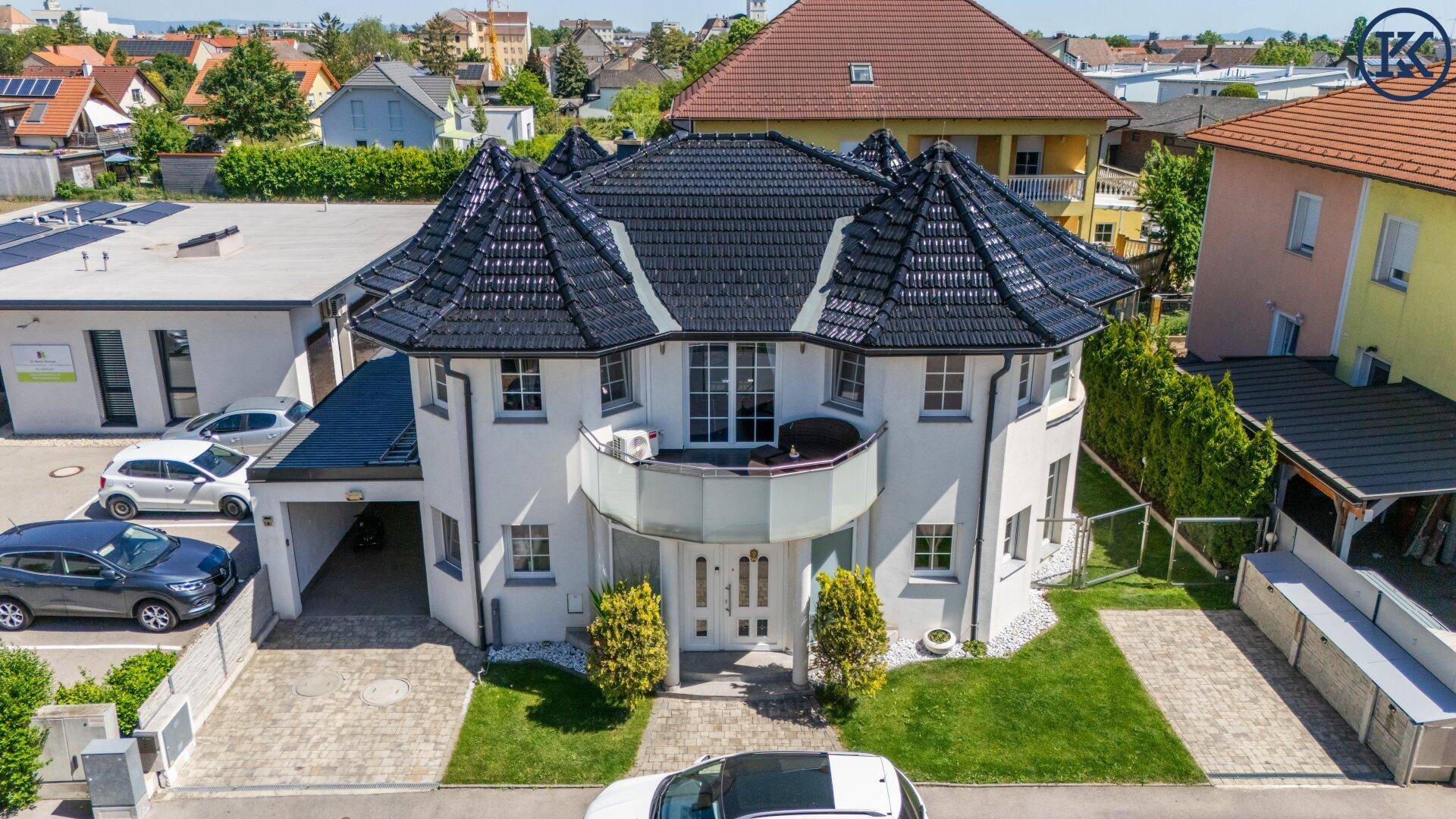 Vorderansicht des modernen Hauses mit eleganter Fassade, gepflegtem Vorgarten und Einfahrt.