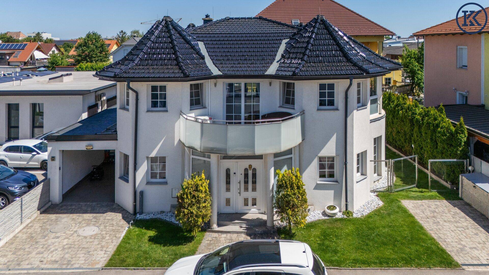 Frontansicht der modernen Villa mit gepflegtem Vorgarten und breiter Zufahrt.
