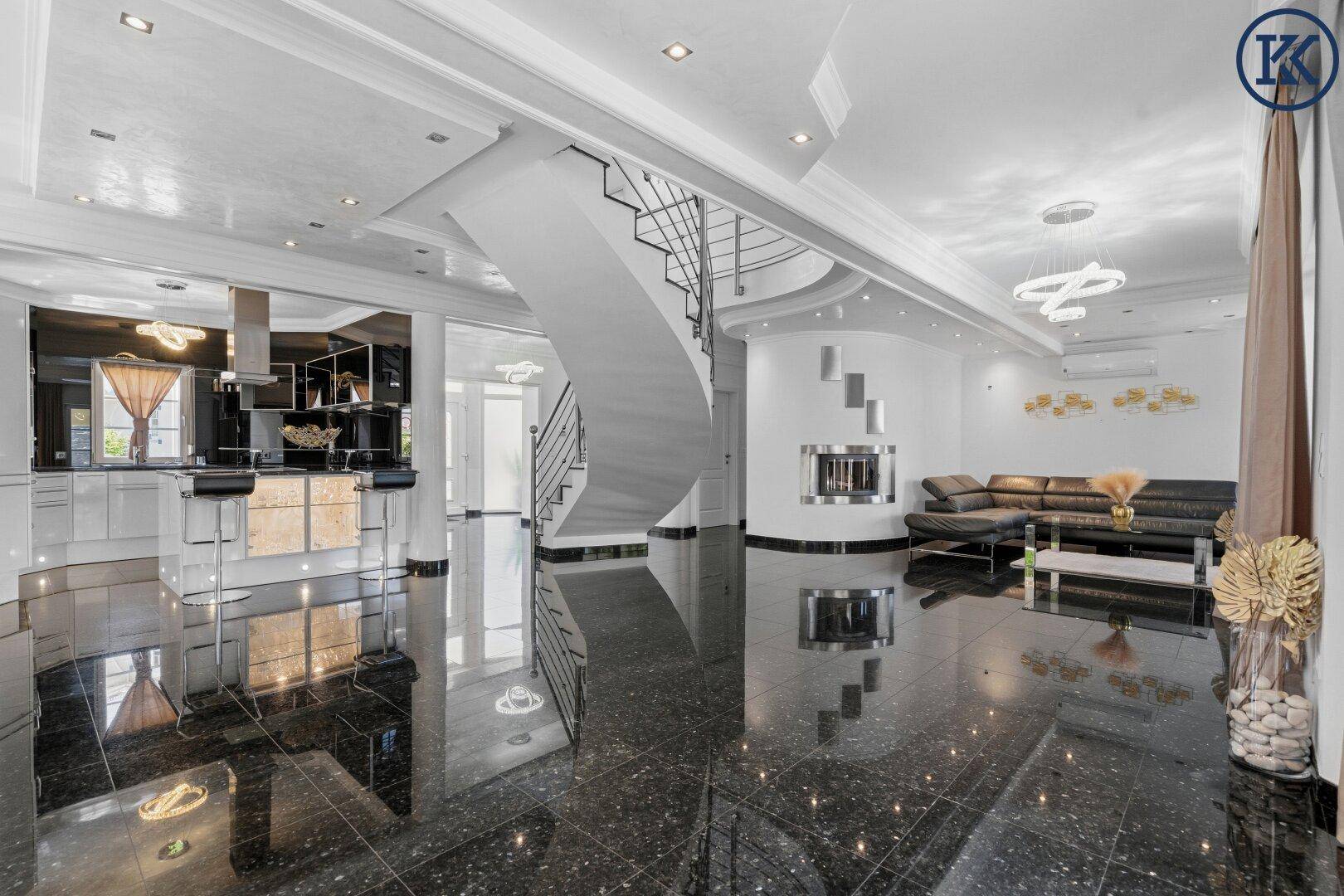 Großzügiger offener Wohnbereich mit Küche, eleganter Treppe und gemütlicher Sofalandschaft.