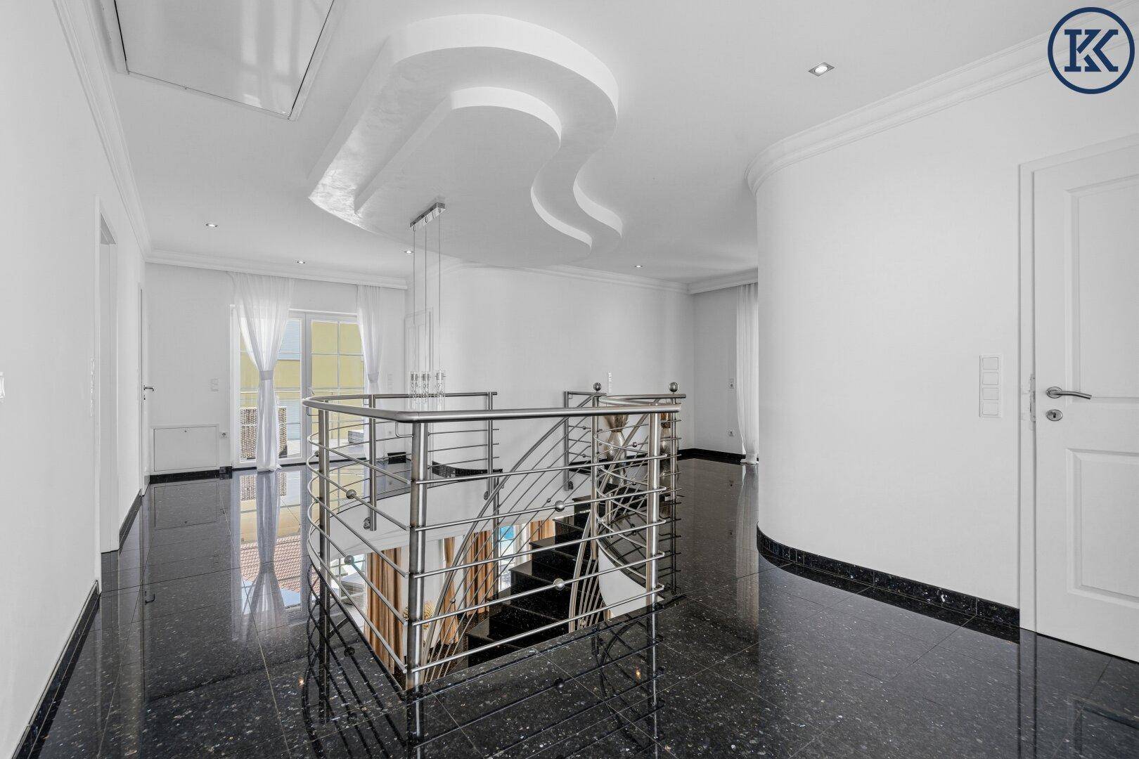Heller Flur im Obergeschoss mit Blick auf die elegante Treppe und moderne Deckengestaltung.