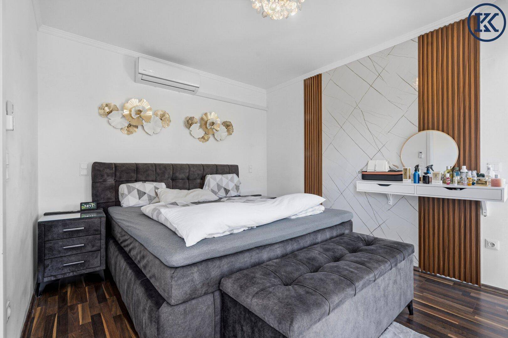 Modernes Schlafzimmer mit großem Boxspringbett, Schminktisch und dekorativer Wandverkleidung.