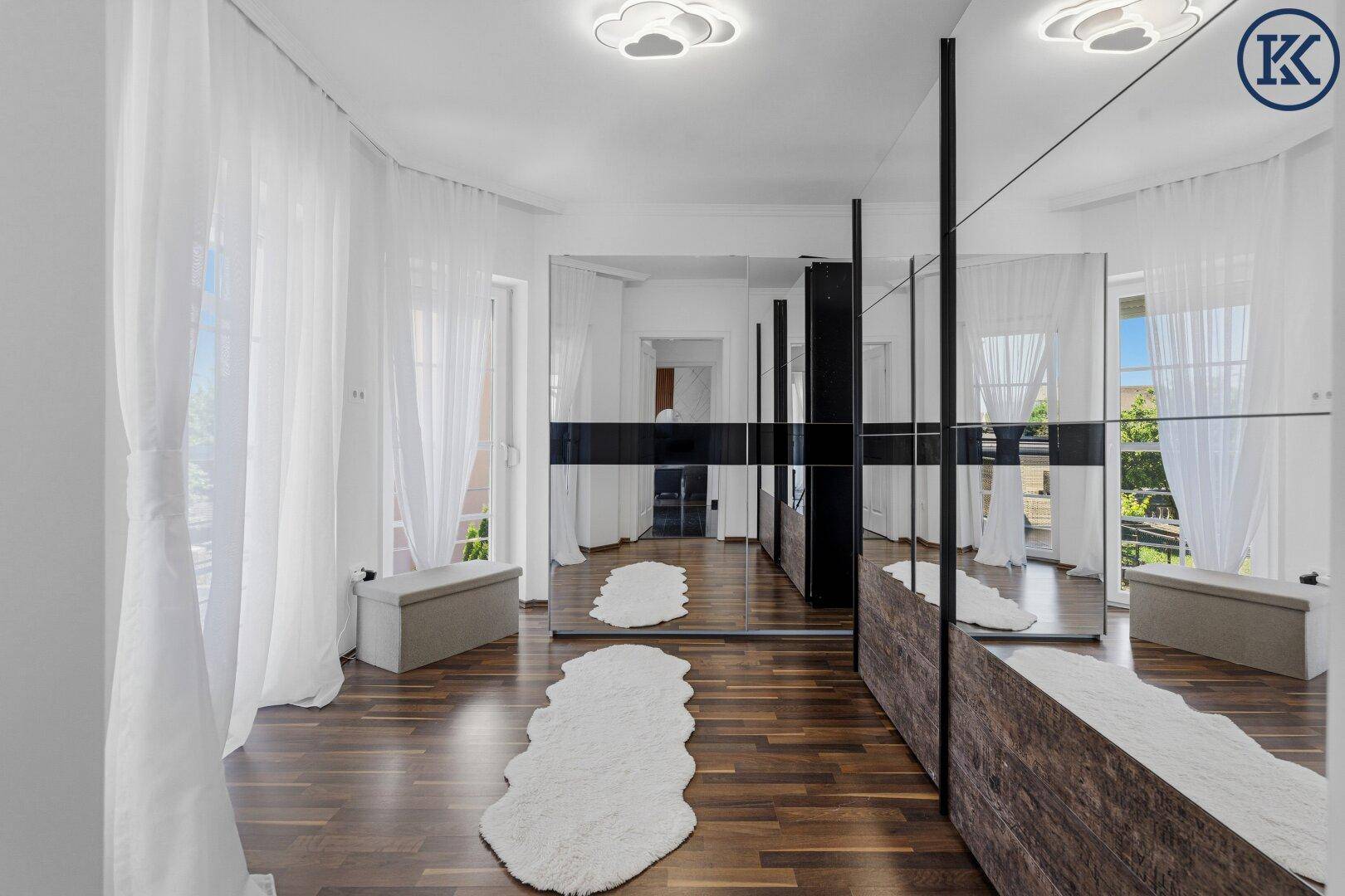 Geräumiger Ankleidebereich mit großen Spiegelschränken und dunklem Holzfußboden.