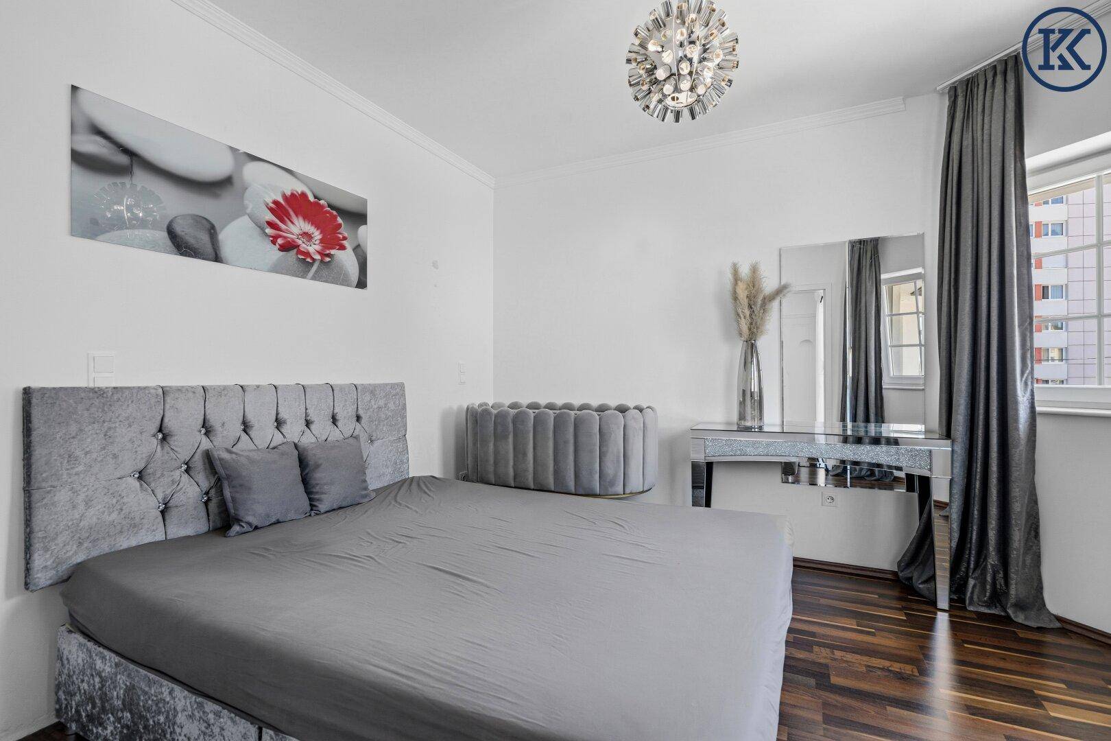 Gemütliches Schlafzimmer mit modernem Bett, dunklem Holzboden und stilvollem Schminktisch.