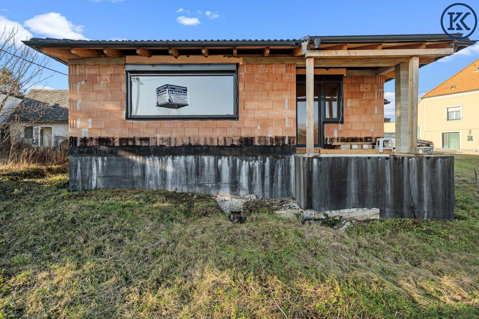 Nahaufnahme eines im Bau befindlichen Hauses mit Ziegelwänden und großen Fenstern.