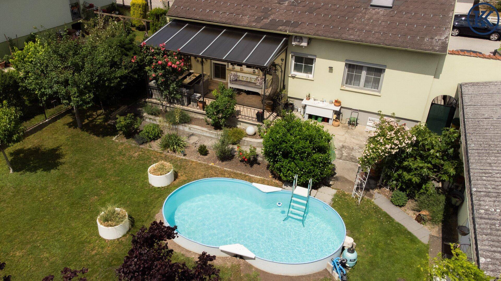 Luftaufnahme des Gartens mit Pool, Terrasse und dem Wohnhaus im Hintergrund.