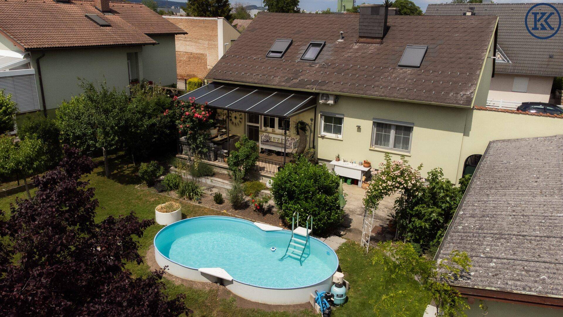 Gesamtansicht des Hauses mit Garten, Pool und überdachter Terrasse von oben.