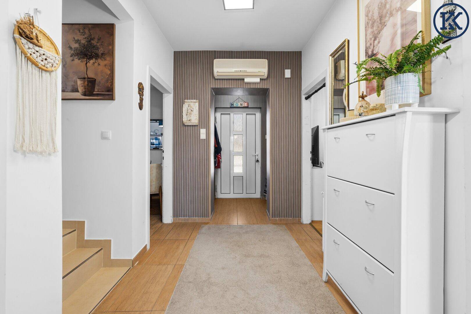 Heller Flur mit Holzfußboden, Teppich, Schuhschrank und Klimaanlage.