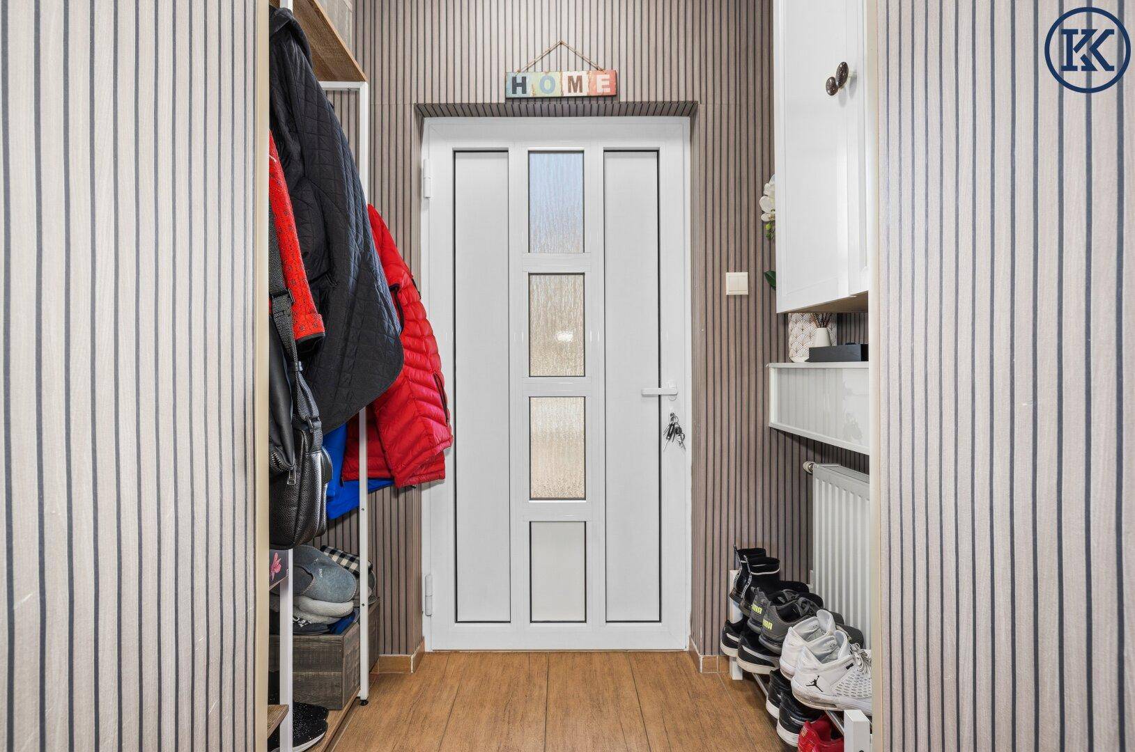 Kleiner Eingangsbereich mit Garderobe, Schuhregal und einer modernen Haustür.