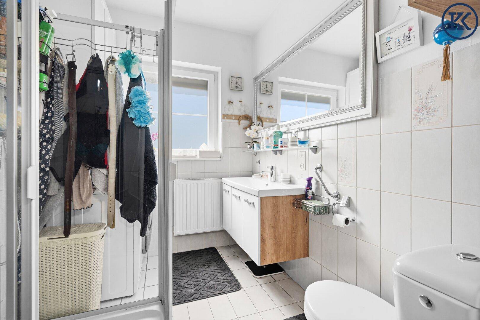 Modernes Badezimmer mit Duschkabine, Waschbecken, Toilette und Fenster für Tageslicht.