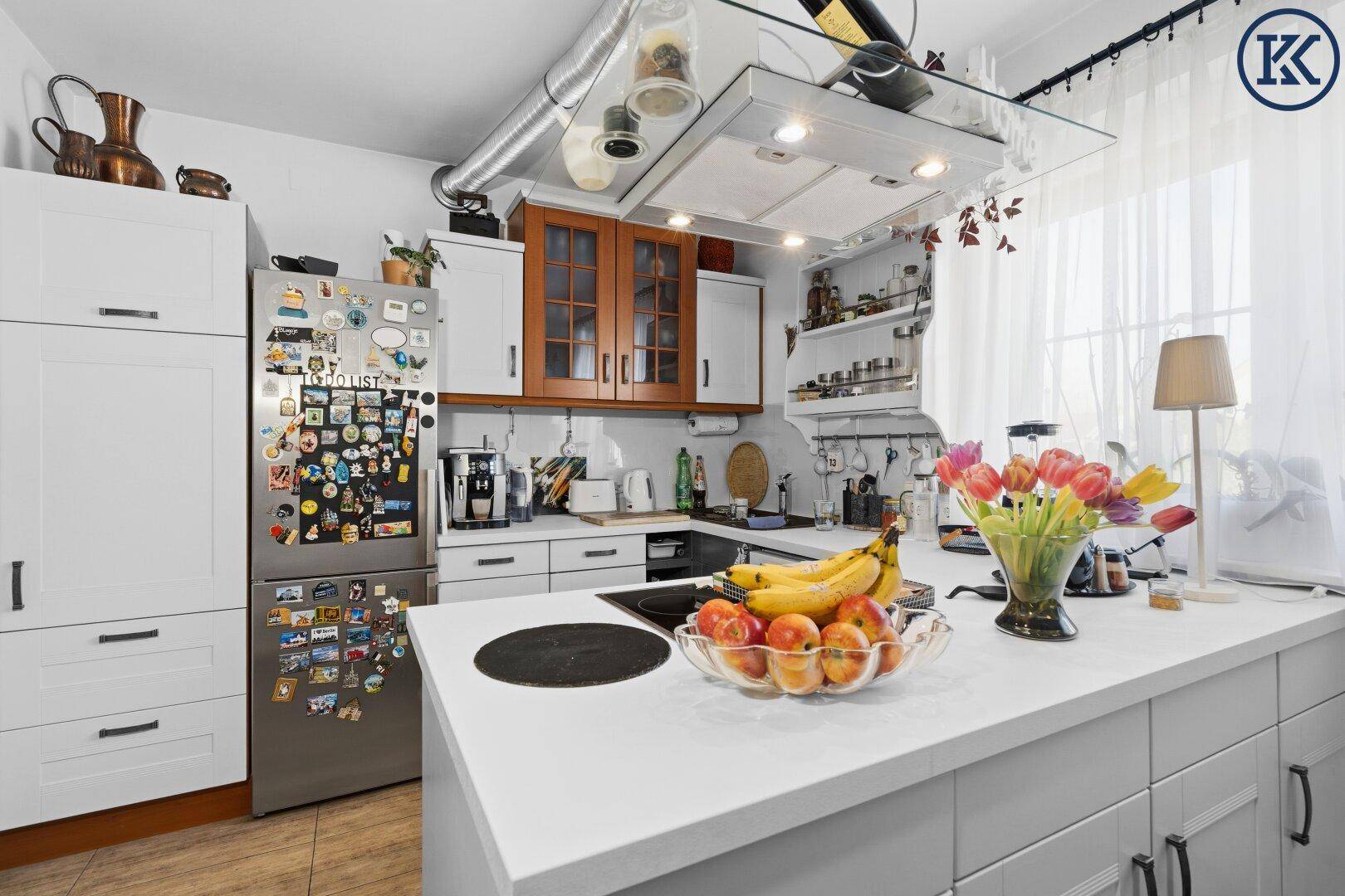 Moderne Küche mit weißen und holzfarbenen Schränken, Kühlschrank und Kücheninsel.