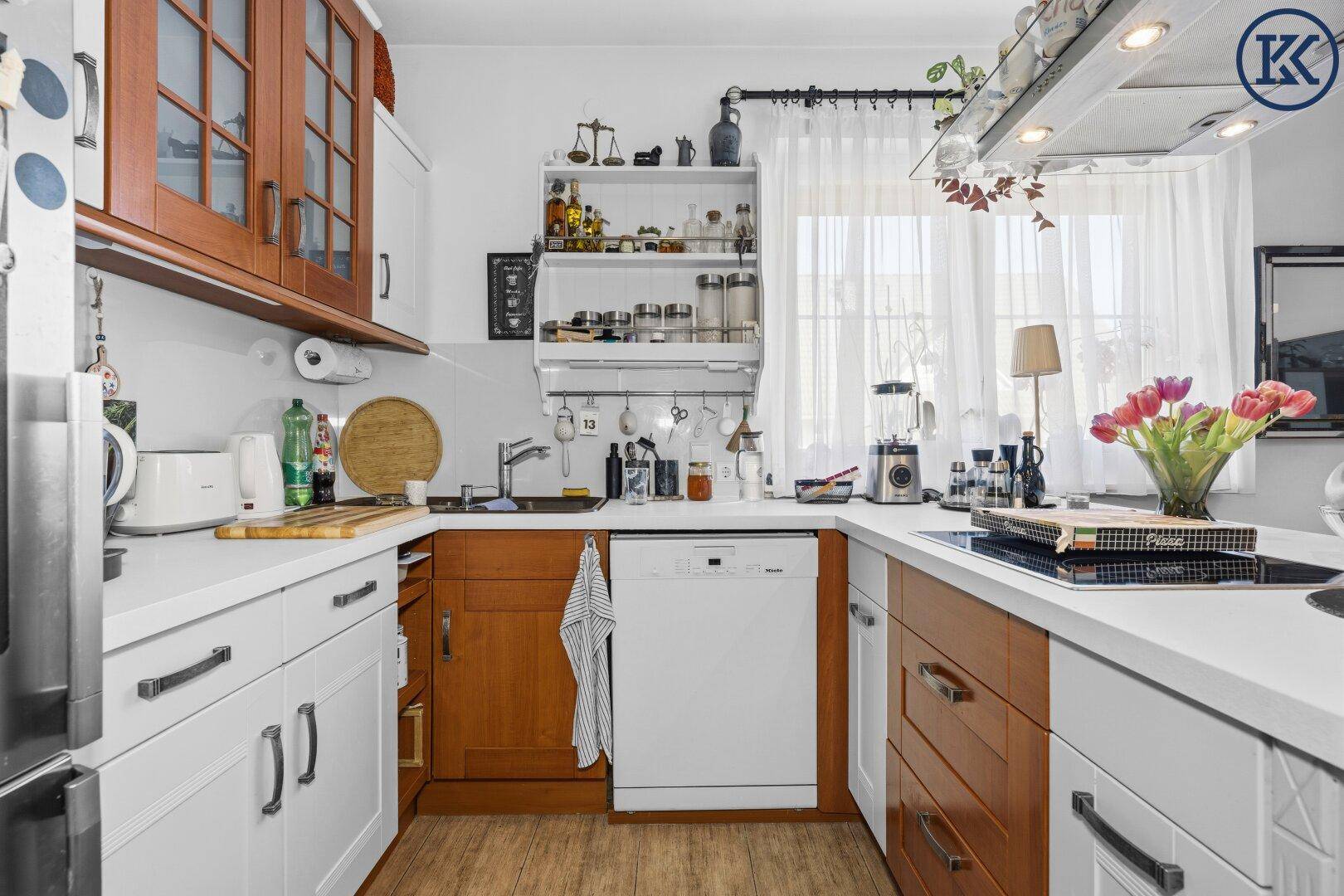 Funktionale Küche mit weißen und holzfarbenen Schränken, Spüle und integriertem Geschirrspüler.