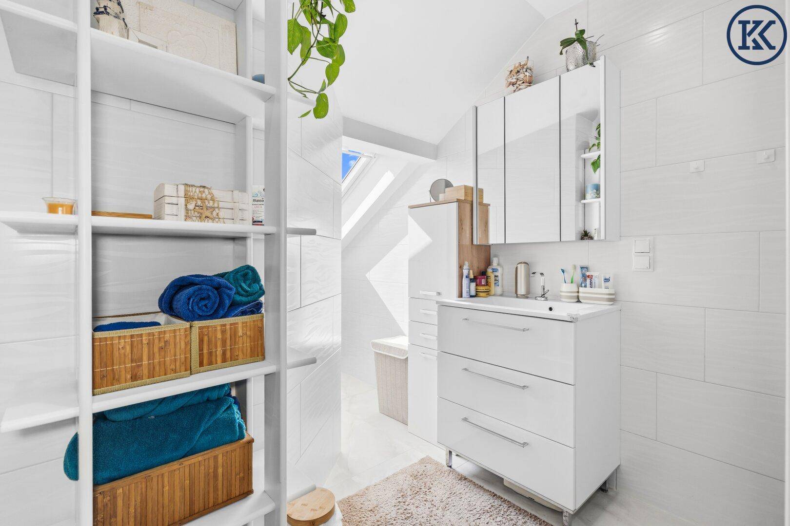 Modernes Badezimmer mit weiß gefliesten Wänden, Waschtisch und praktischen Regalen.