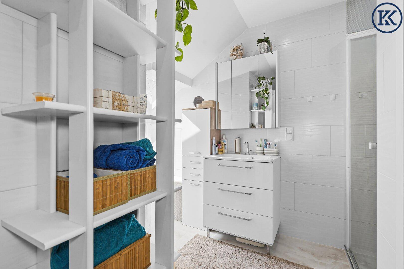 Helles Badezimmer mit Waschtisch, Spiegelschrank und offenem Regal für Handtücher.