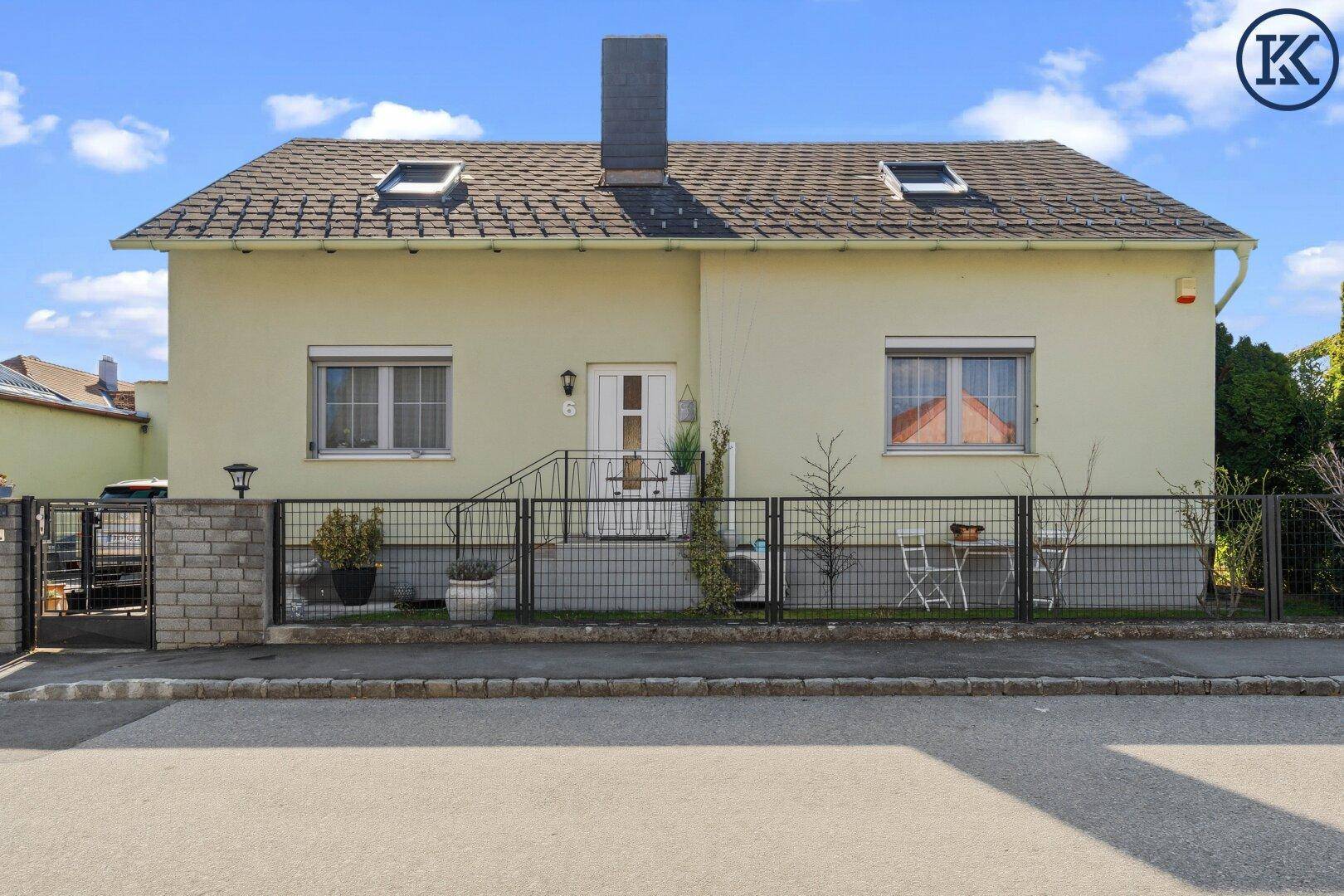 Frontansicht des Hauses mit gepflegtem Vorgarten, Zaun und Eingangsbereich.