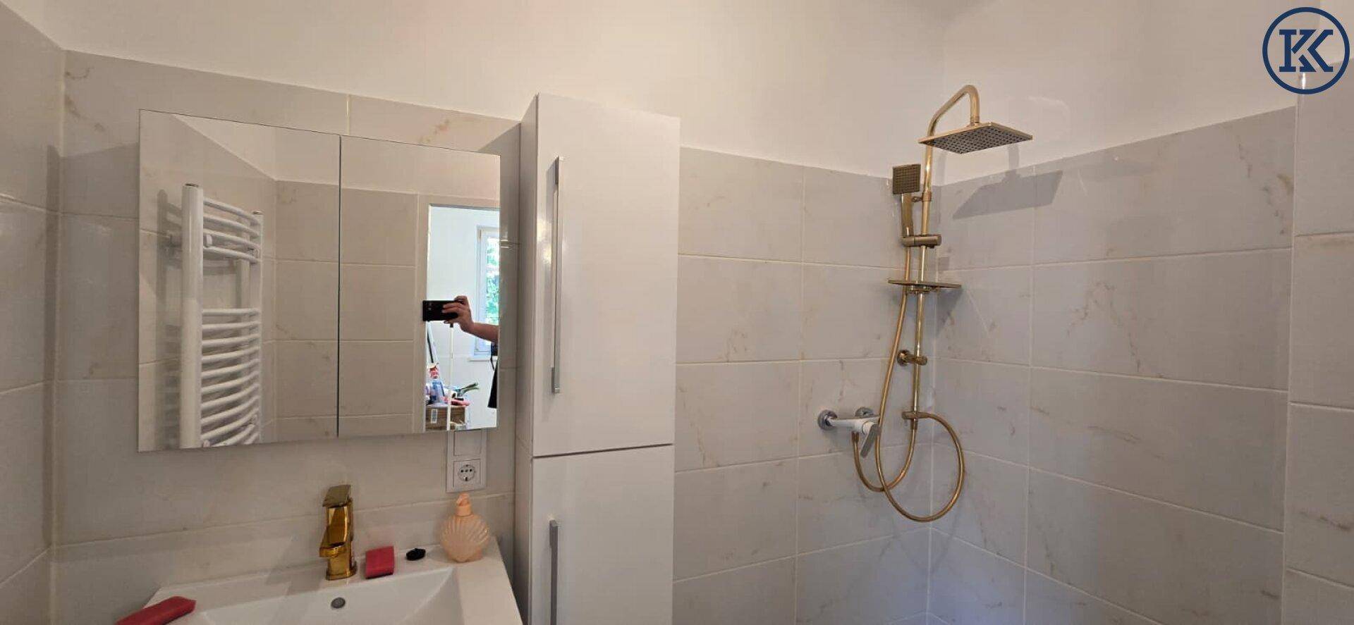 Modernes Badezimmer mit Duschbereich, Einzelwaschbecken und Spiegelschrank.