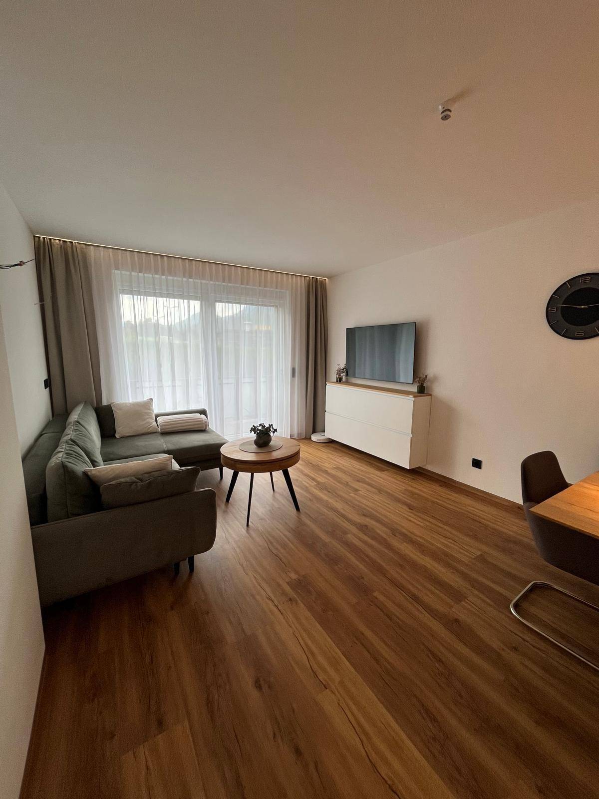 Gemütlicher Wohnbereich mit Ecksofa, Holzboden und Zugang zu einem Balkon.