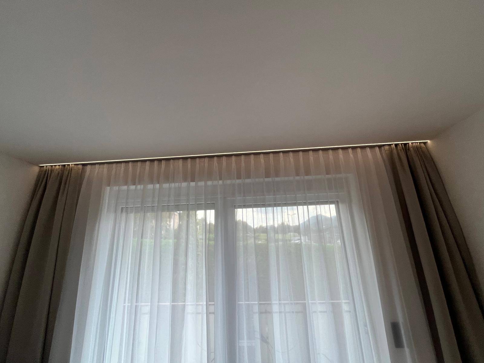Große Fensterfront mit Vorhängen, die viel natürliches Licht in den Raum lässt.