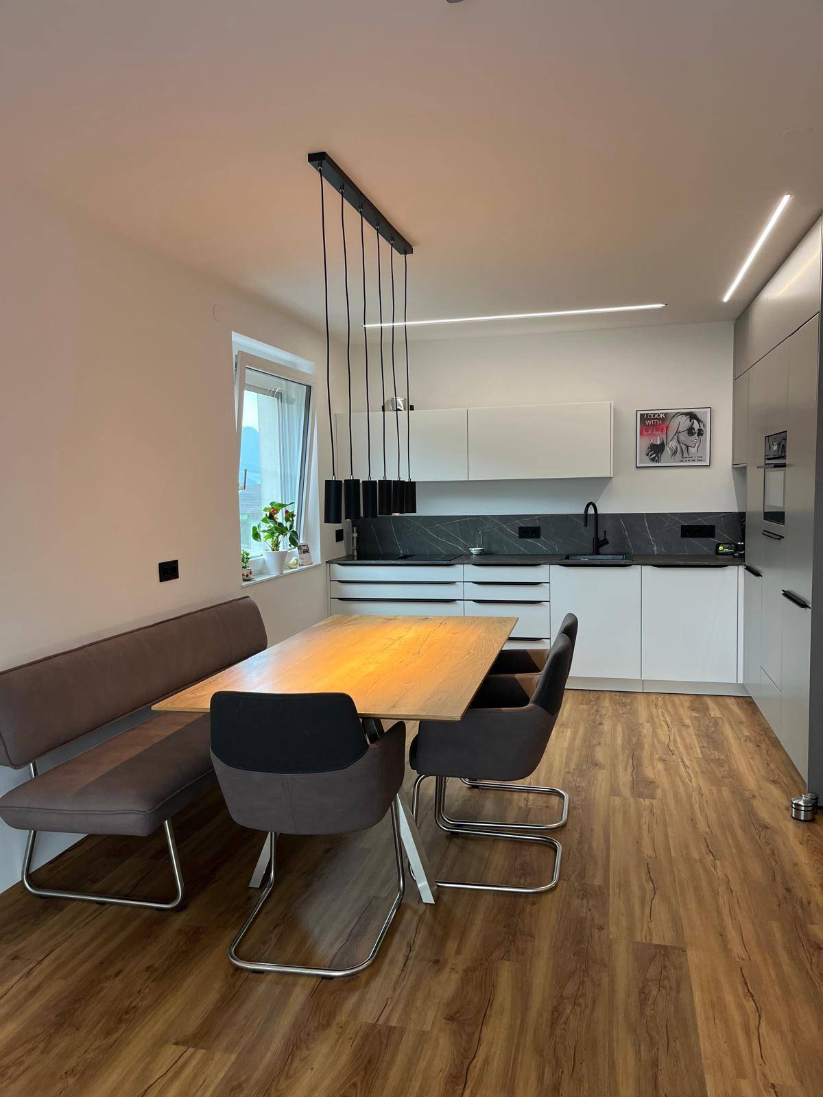 Heller Essbereich mit Holztisch und moderner Hängelampe, offen zur Küche.