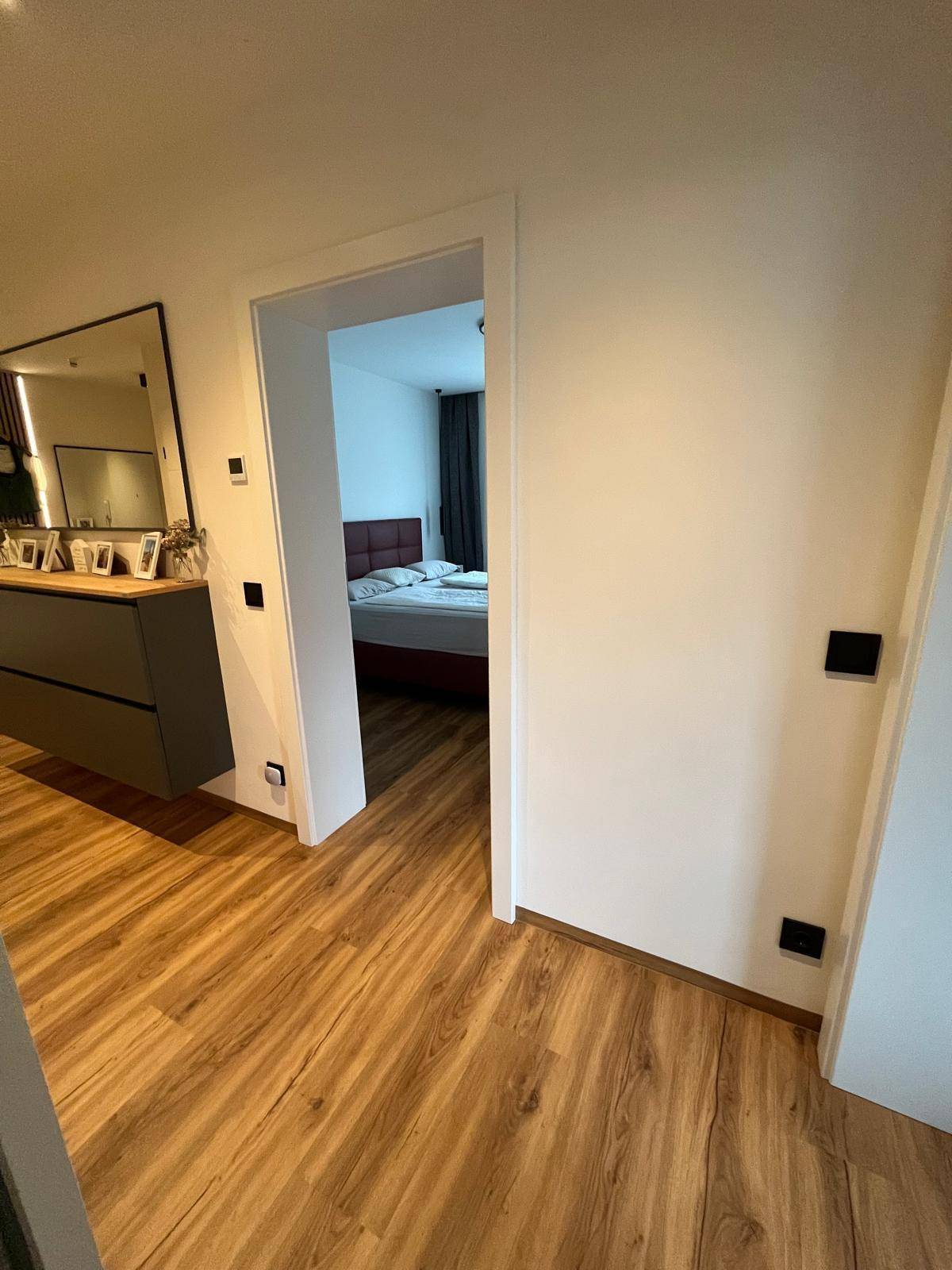 Heller Flur mit Laminatboden, der direkt in ein gemütliches Schlafzimmer führt.